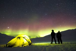 a neon tent underneath the northern lights