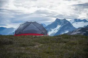 a screen tent on some grass in front of a mountain